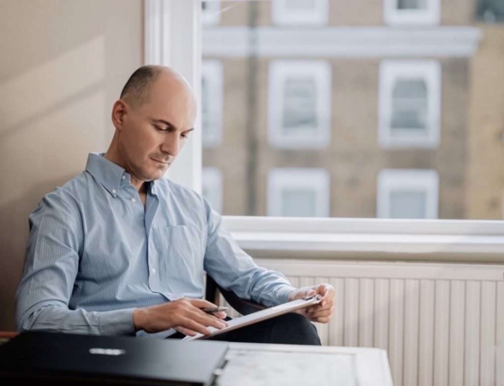 Dr John Tsagaris reviewing clinical notes and research literature at his Harley Street practice